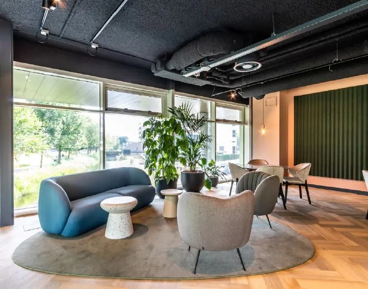 Moderne loungehoek met designmeubels en grote planten in een kantoor aan het John M. Keynesplein.